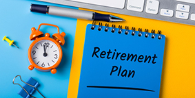 Image of a keyboard, pen and alarm clock next to a retirement plan notebook