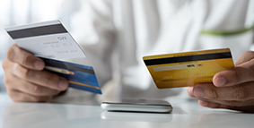 A person holding three credit cards in his hands as if trying to figure out which card to use