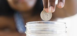 Hand depositing change in a glass jar